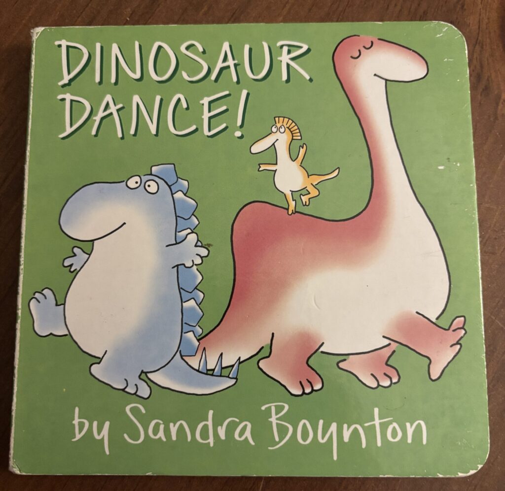 a baby book with dinosaurs dancing on the cover